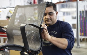  	A male manufacturing associate works on the backside of a chair.